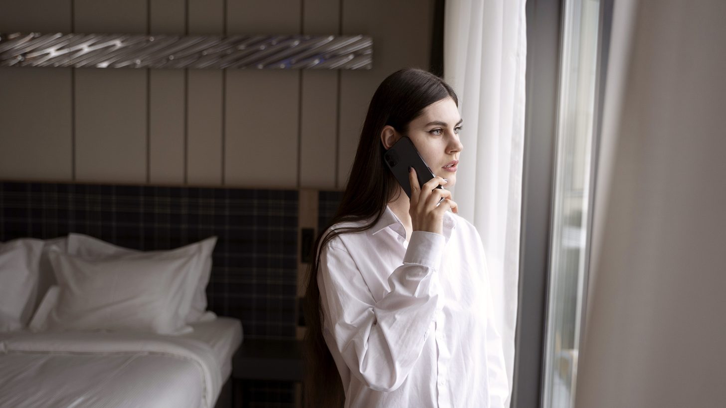 A traveller alone in a hotel room speaking on a phone