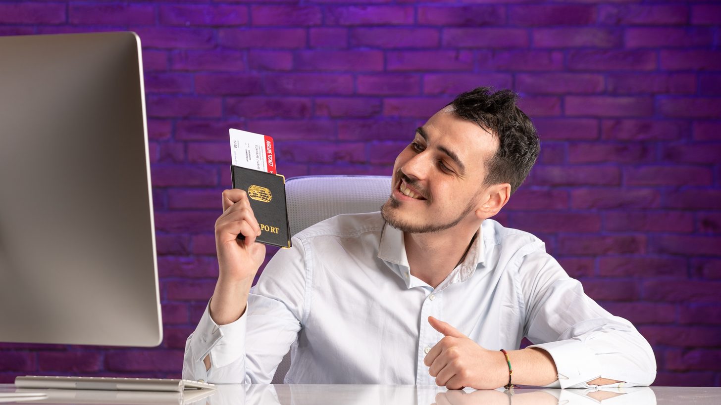A travel agent at a desk holding a passport and travel documents