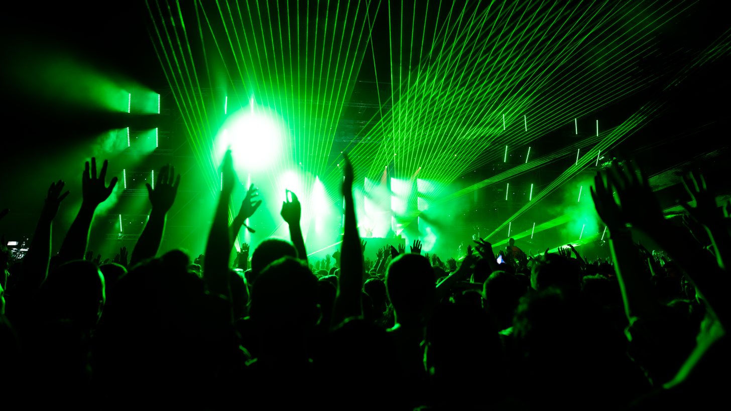 A DJ performing in front of a festival crowd at night