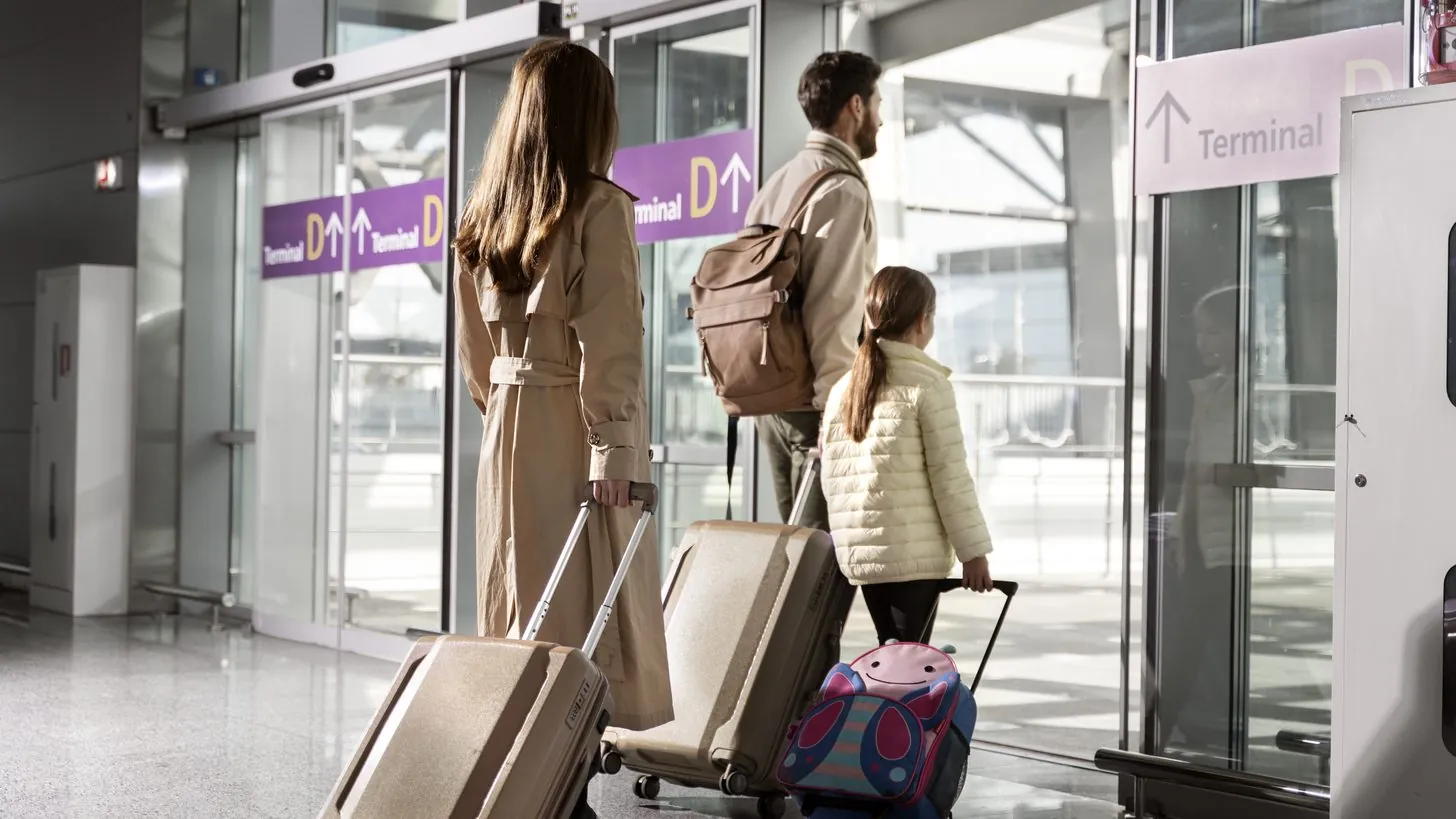 Travellers walking with luggage through an airport waiting area