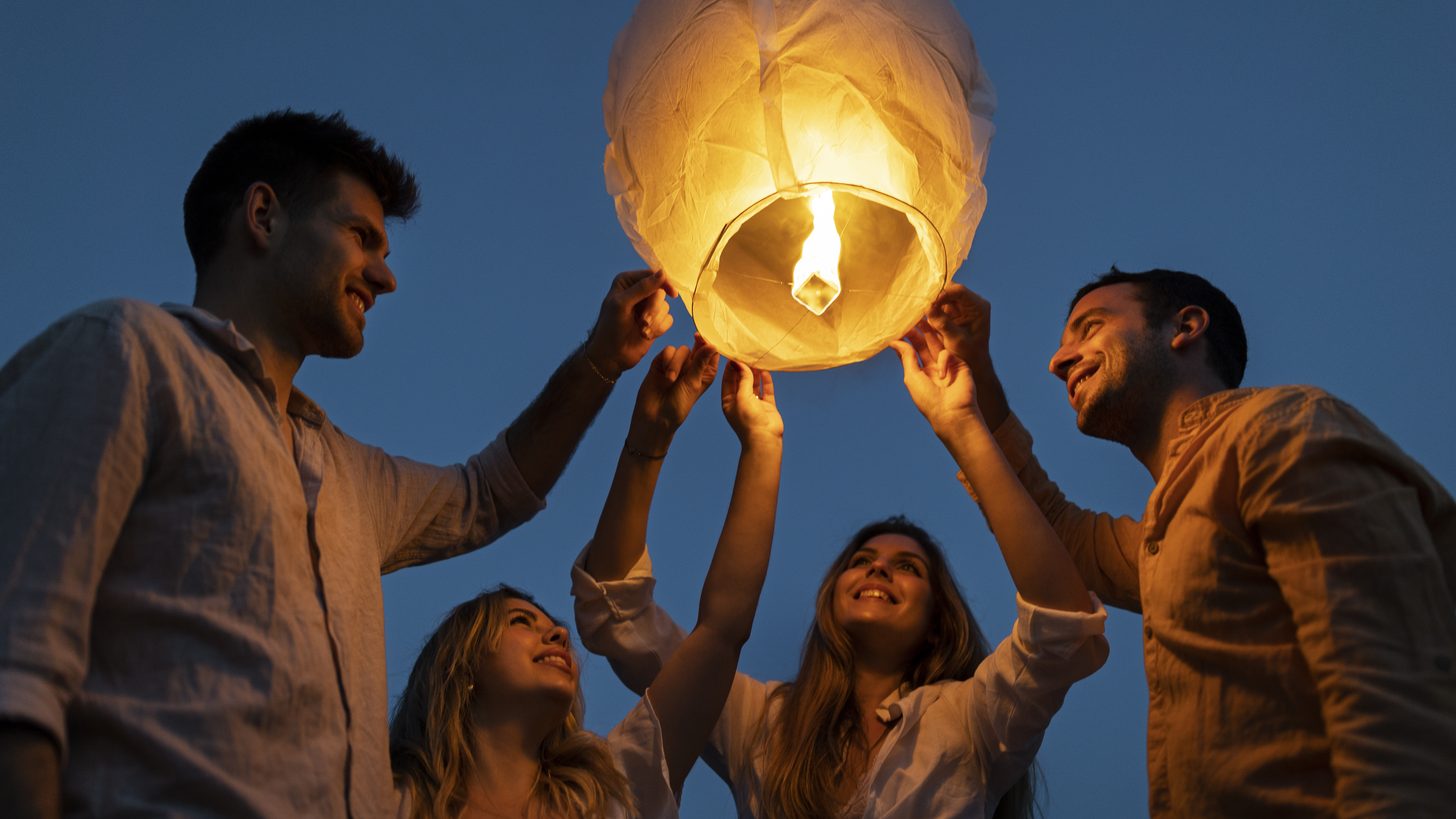 People releasing a glowing lantern into the night sky