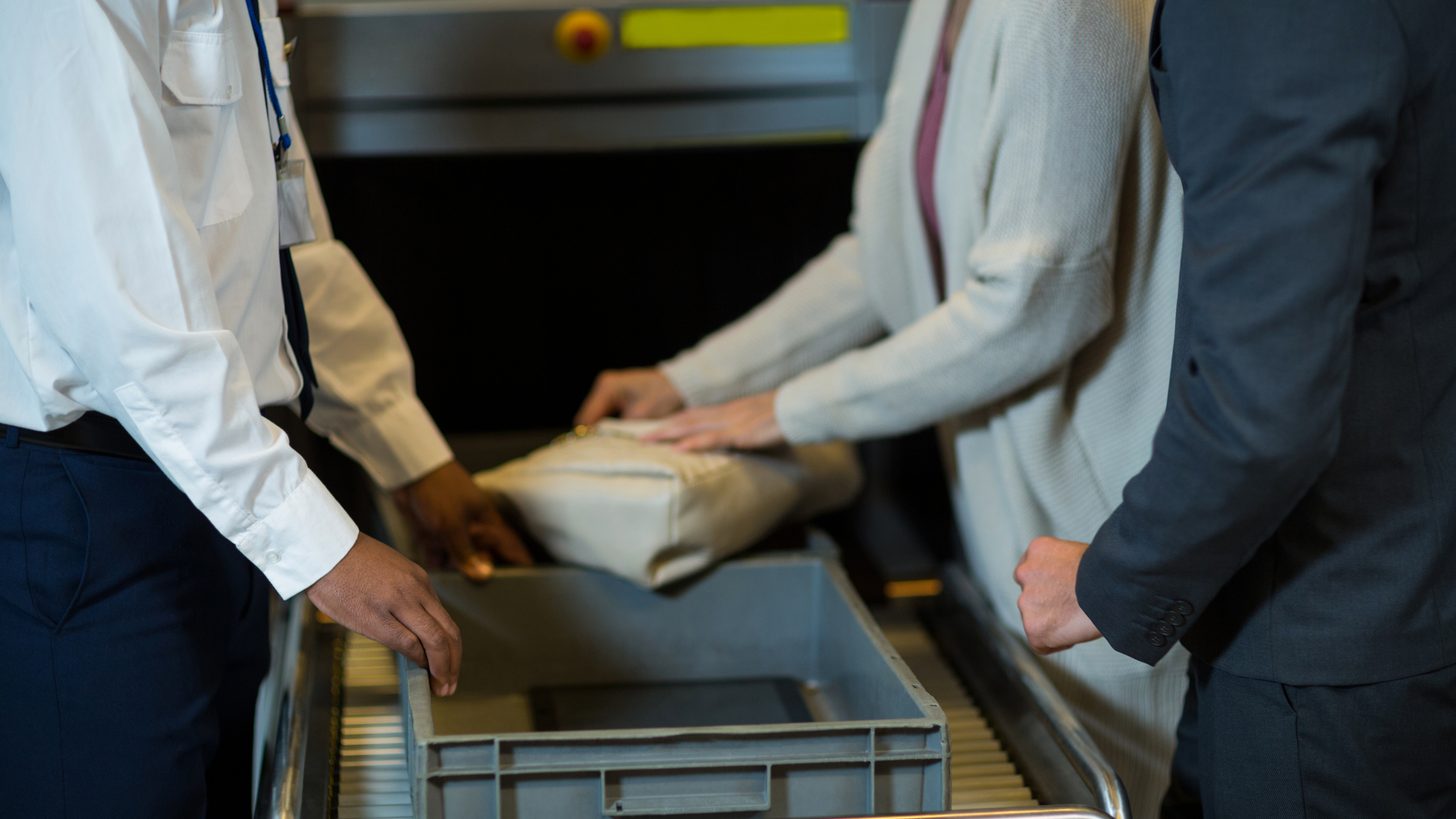 Passengers with hand luggage passing through an airport security screening area