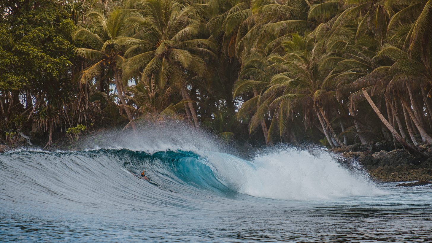 Waves breaking on a rocky Thai shoreline under a grey monsoon sky