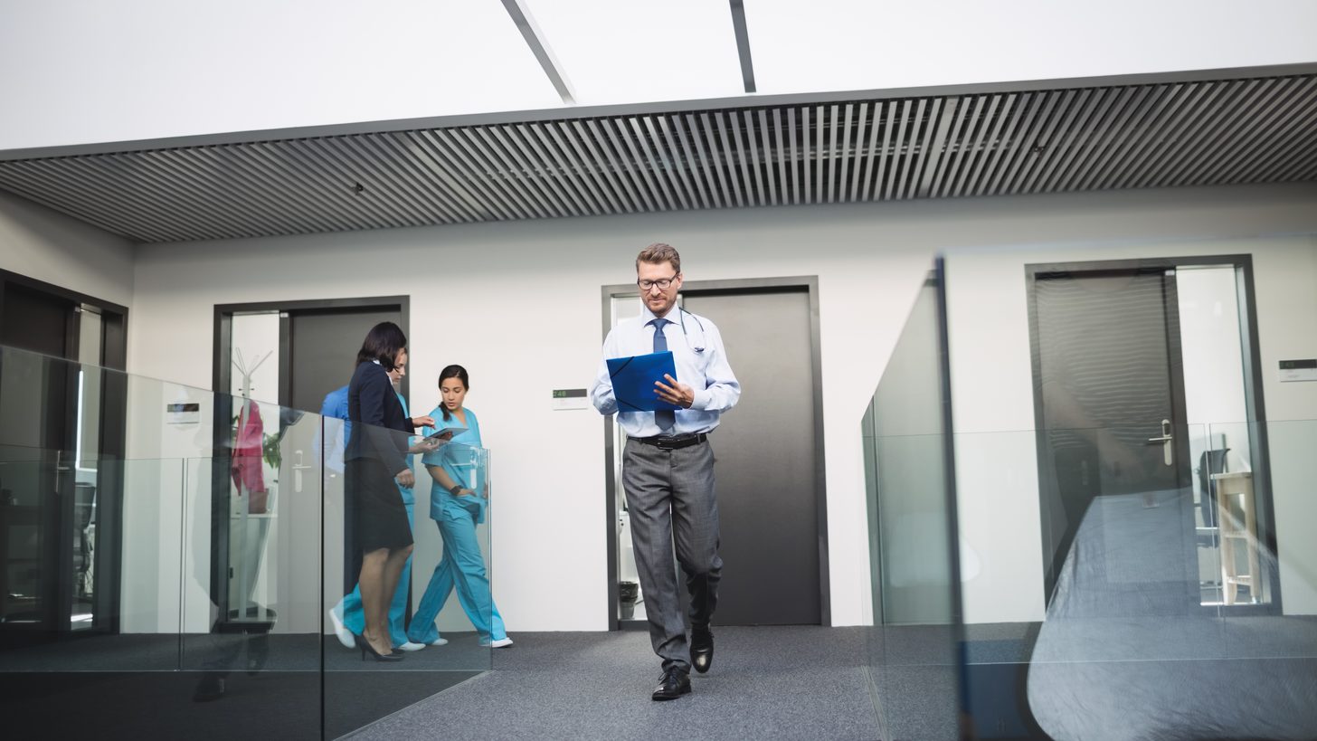 Doctors and a nurse walking together along a bright hospital corridor