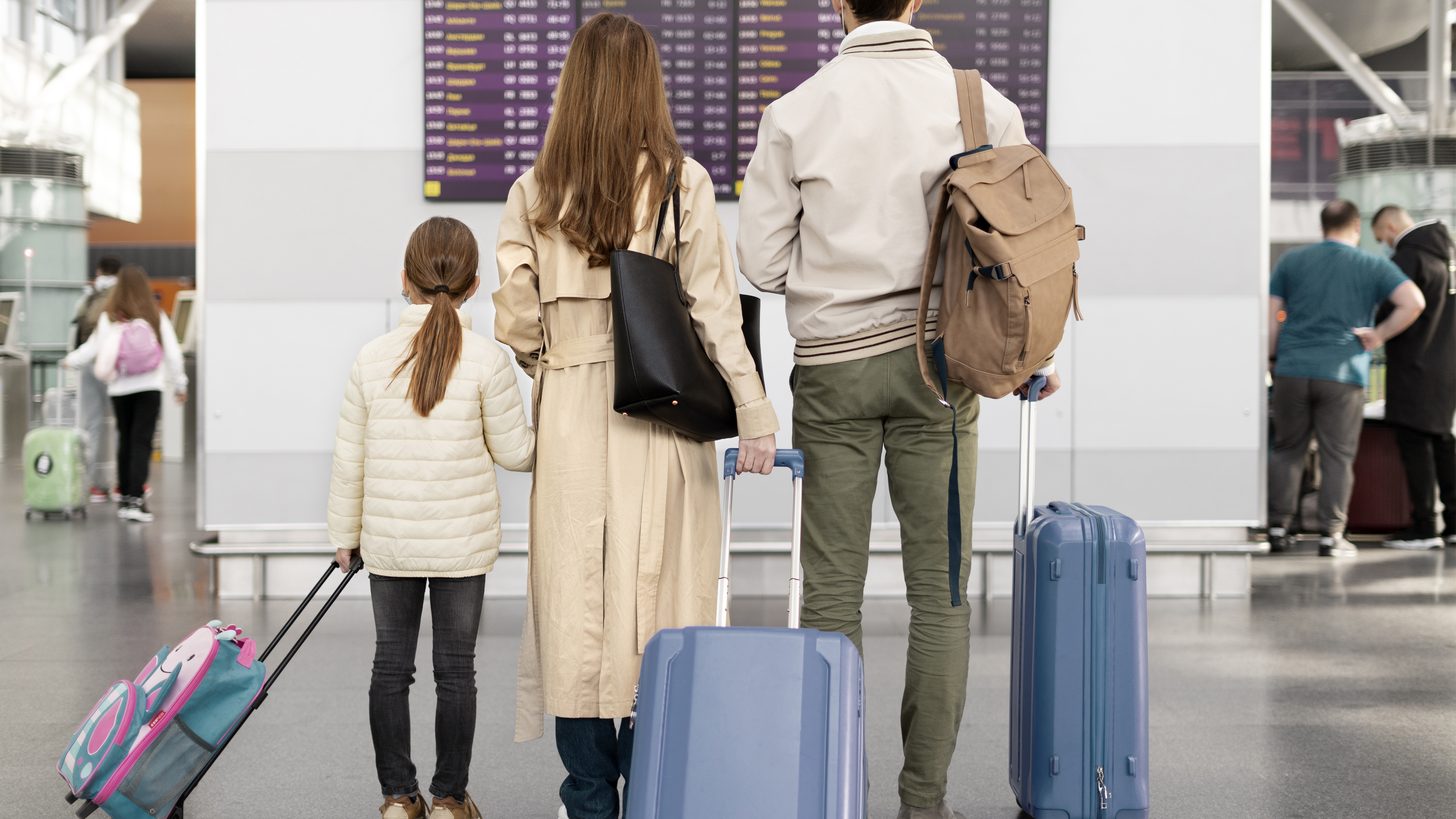 A family with young children waiting with luggage in an airport terminal