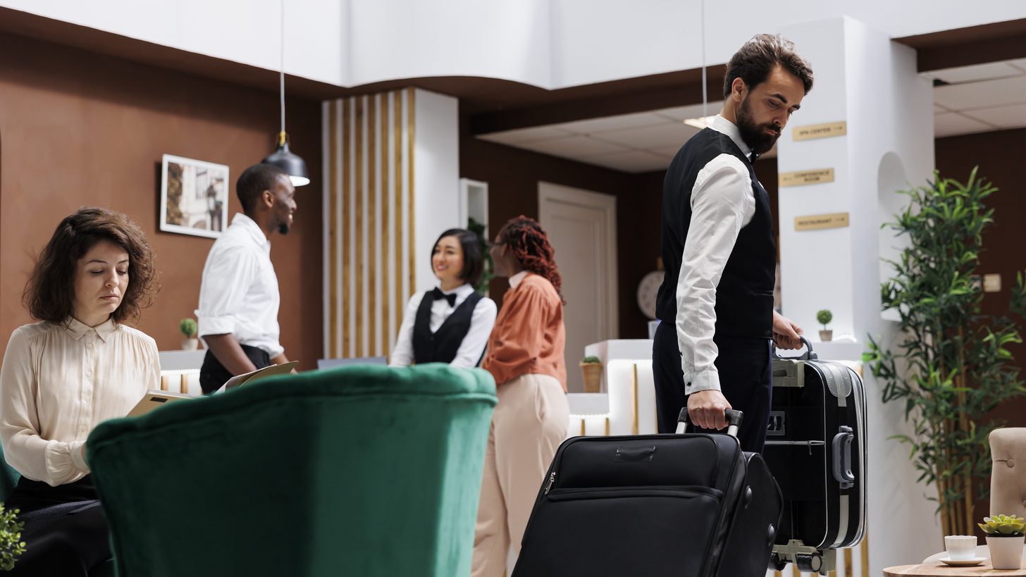 A hotel lobby with luggage trolleys and guests waiting near reception