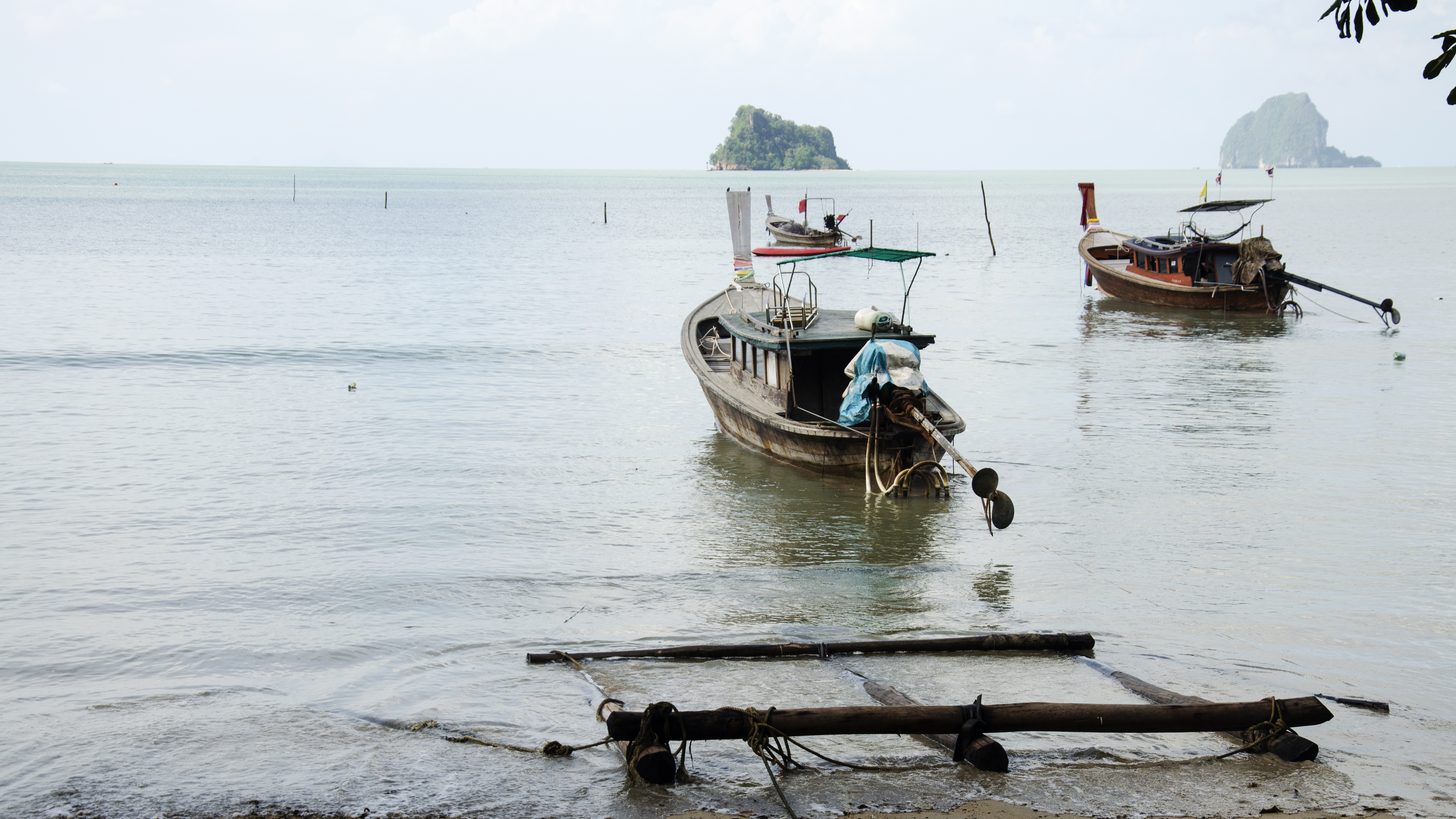 A passenger ferry moored at a tropical island pier with travellers waiting to board