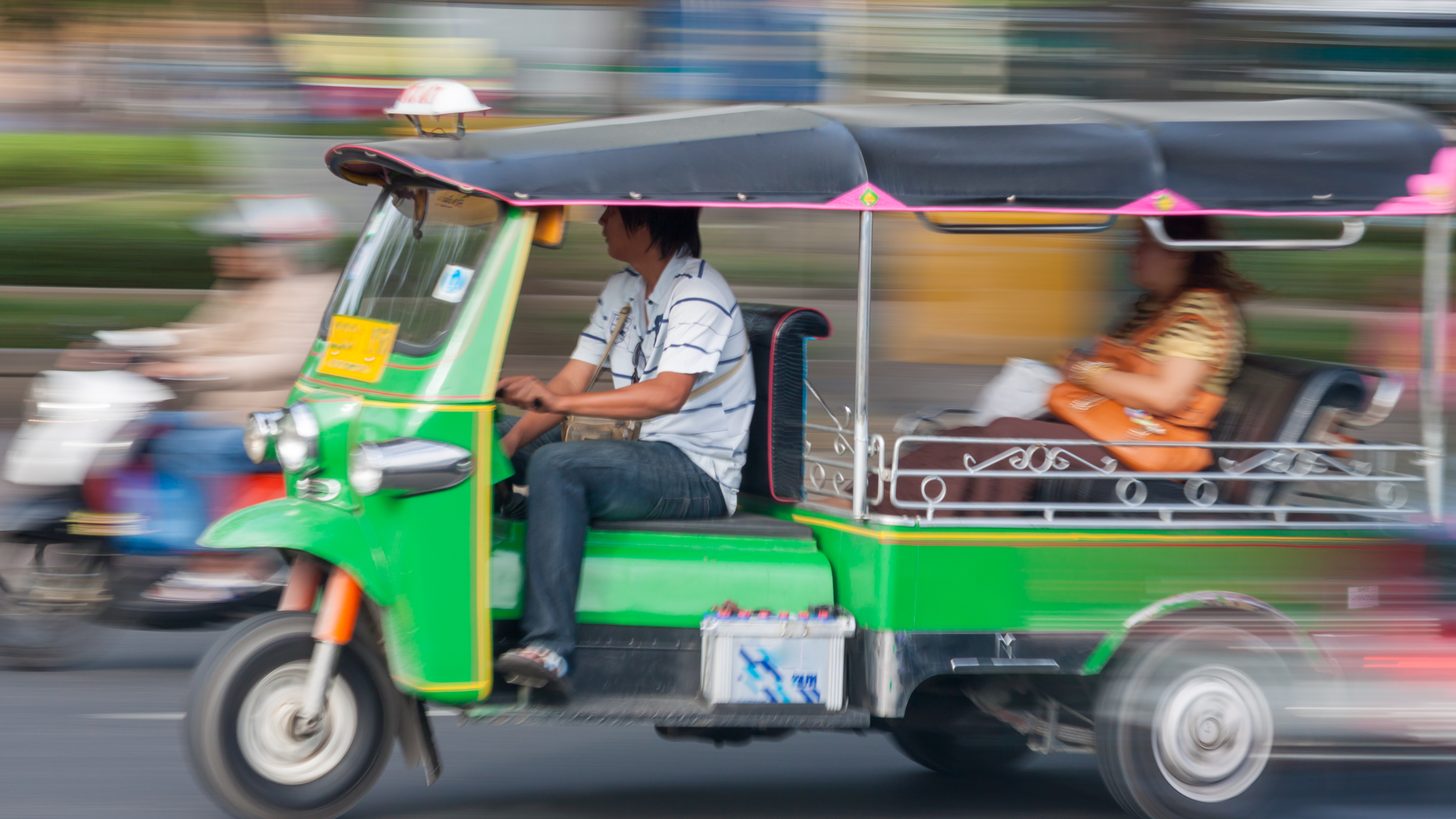 A tuk-tuk moving through Bangkok traffic