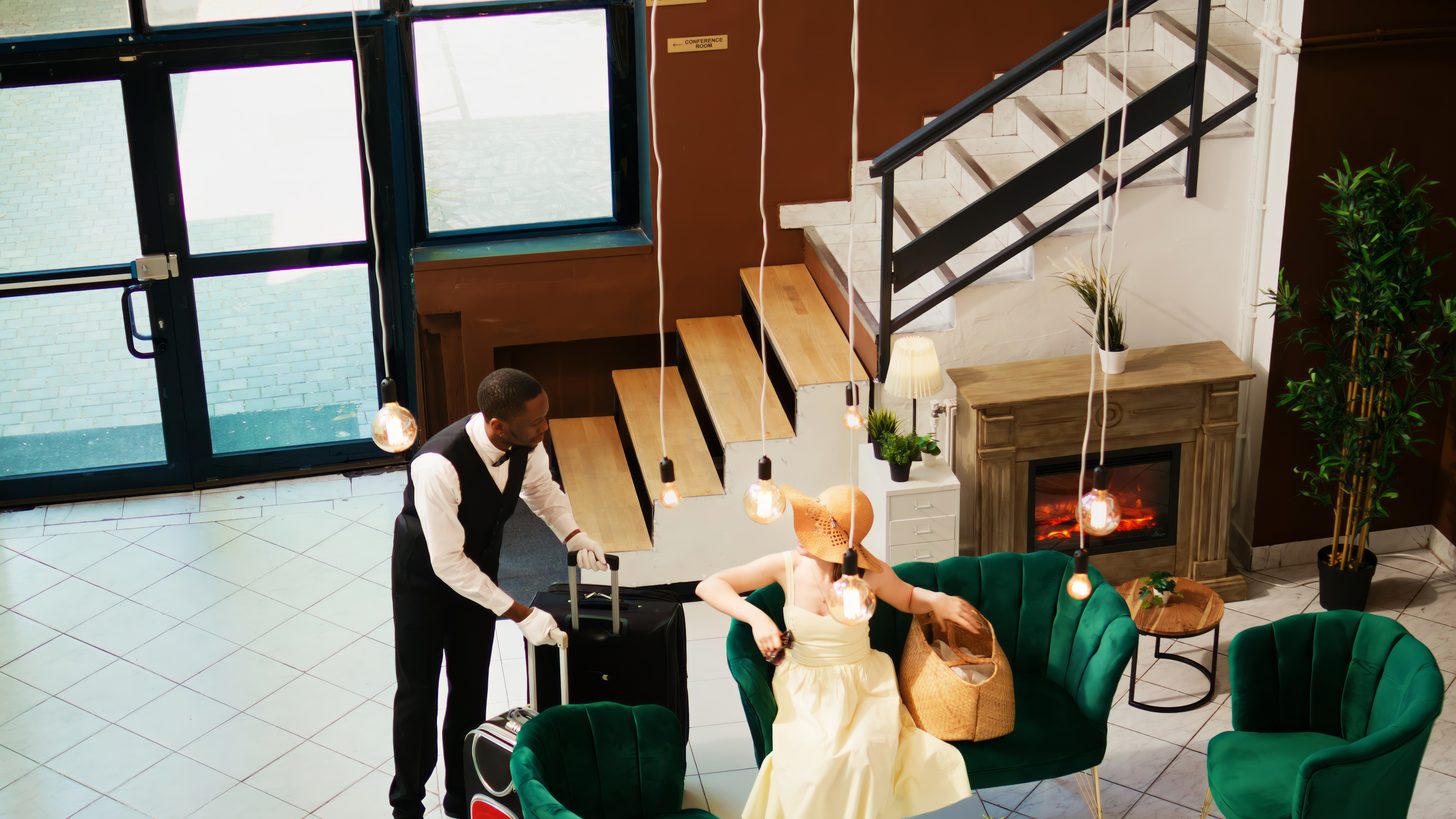 A hotel concierge carrying guest luggage through a lobby