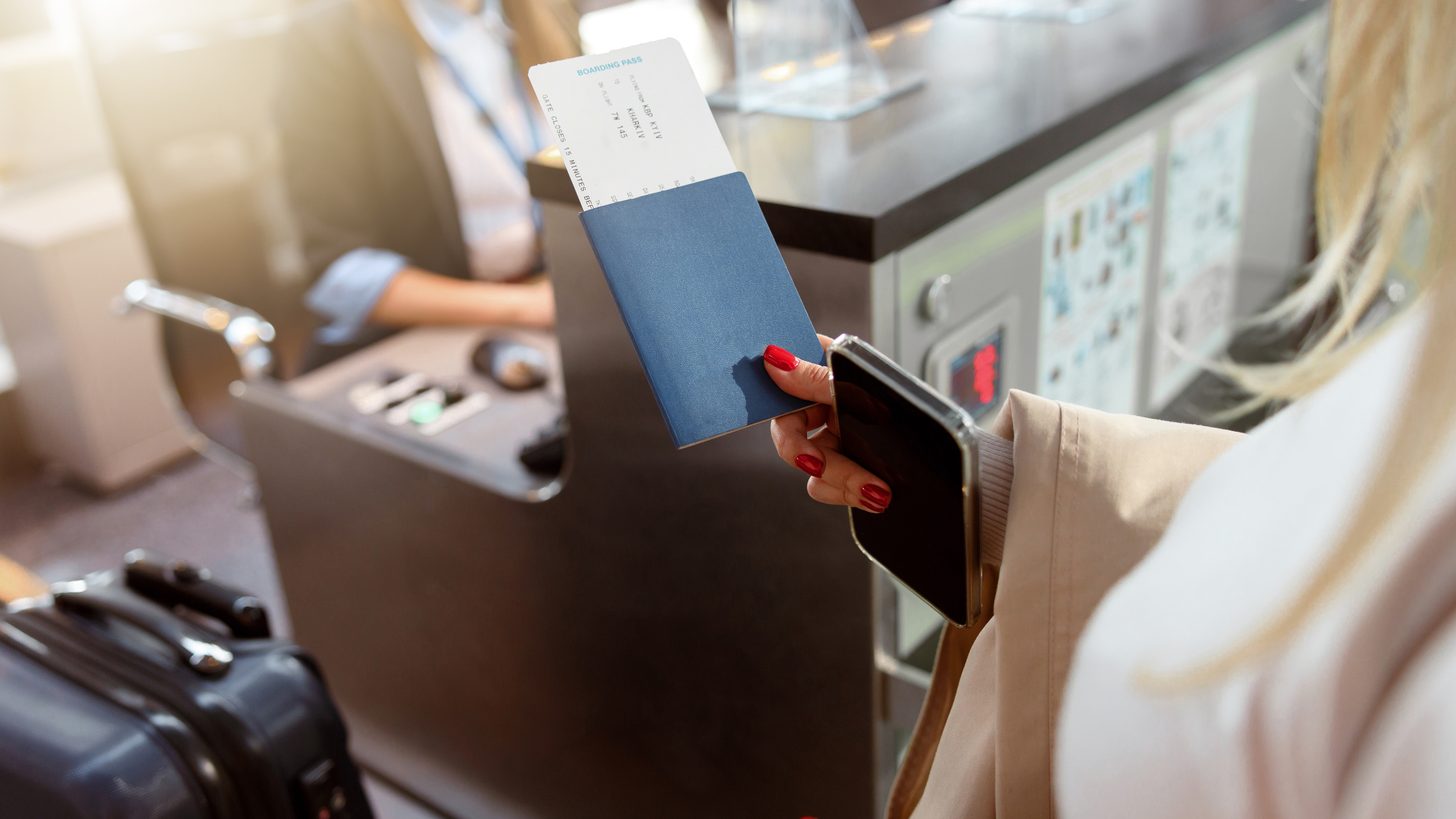 A traveller holding a passport and tickets at a reception desk