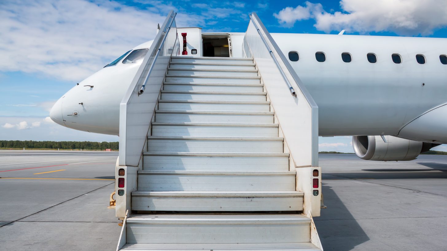 An aircraft on the apron at a regional airport with boarding stairs in place