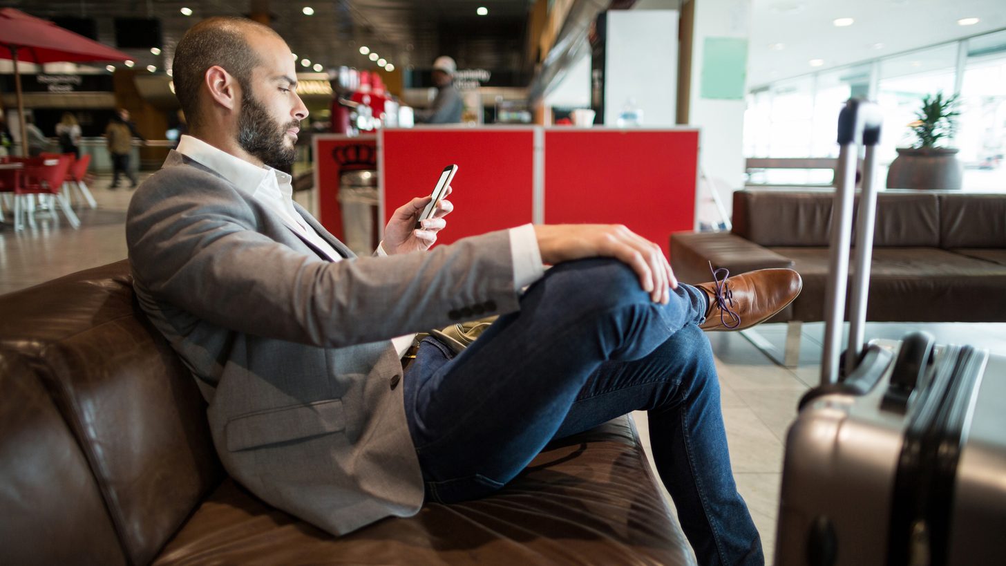 A person taking a phone call while waiting, papers in hand