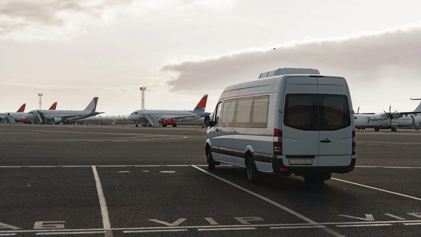 Ein Minibus mit Fahrer wartet vor einem Ankunftsterminal auf Fahrgäste