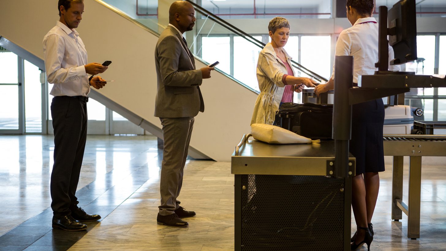 Passengers queuing with luggage at an airline check-in counter