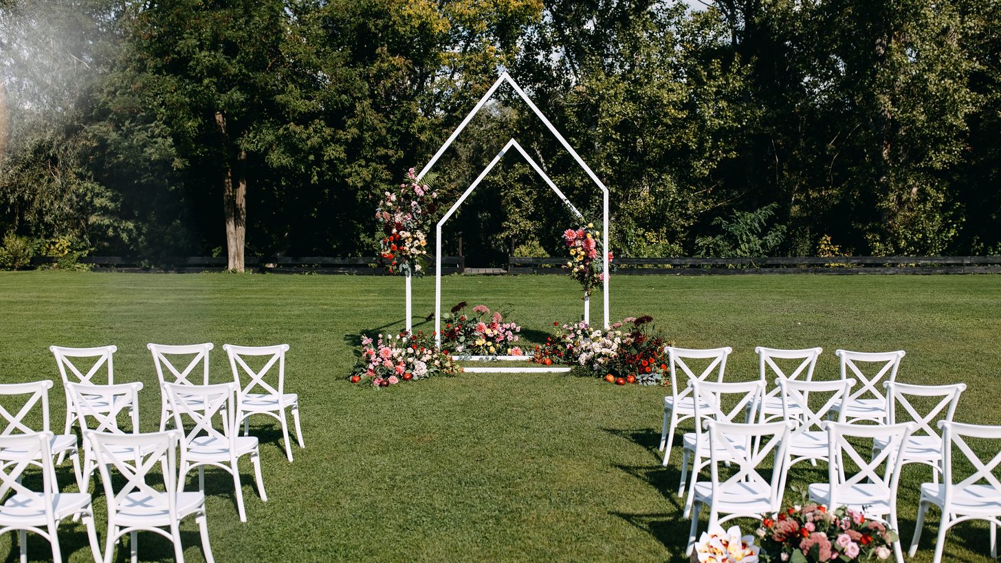 A decorated outdoor event setting with chairs arranged for a ceremony