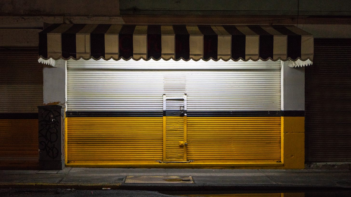 A metal shutter pulled down over a closed shopfront at night