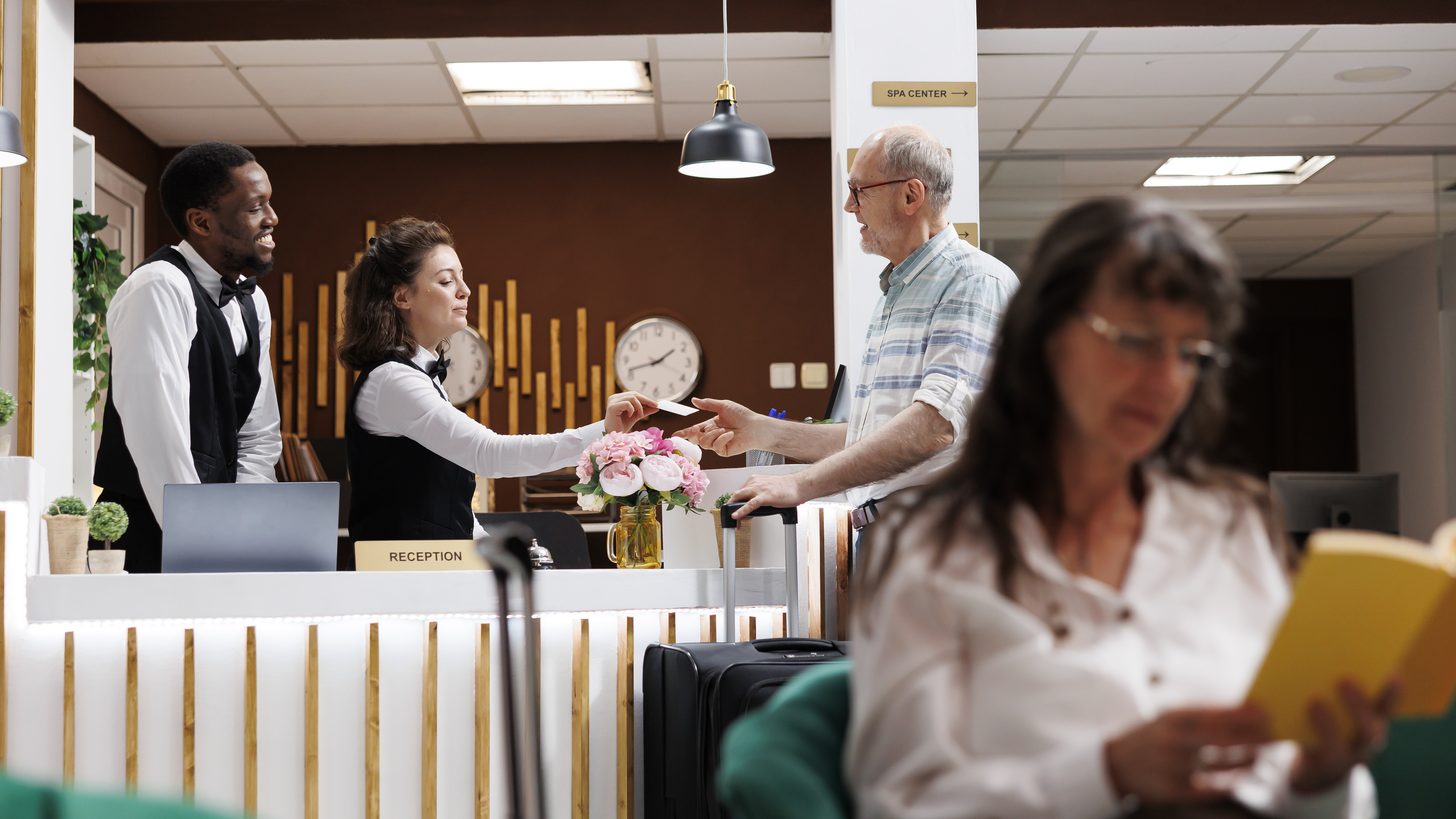 A receptionist welcoming arriving guests at a hotel front desk