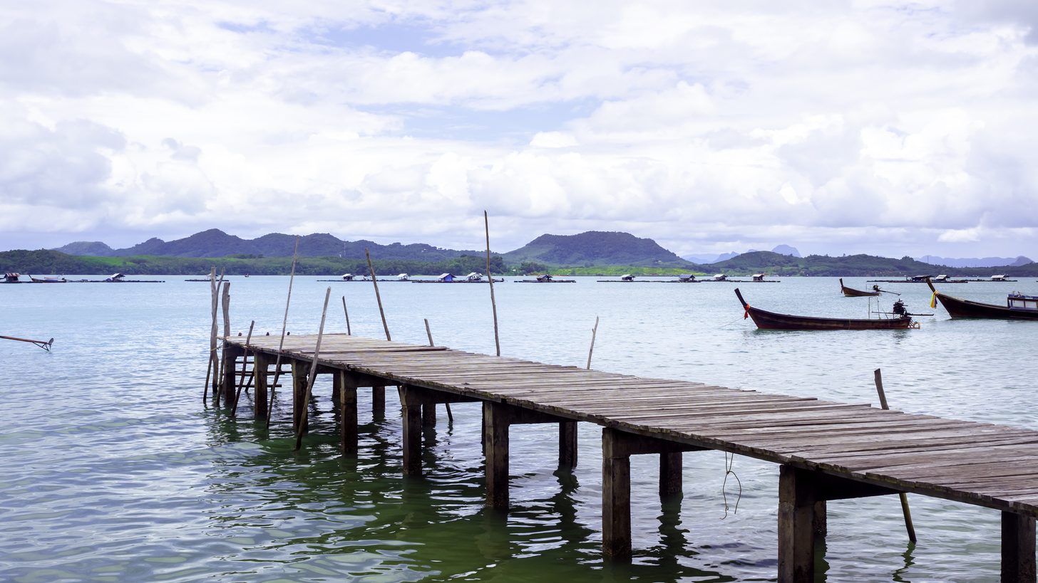 Boats moored at a pier under an overcast sky