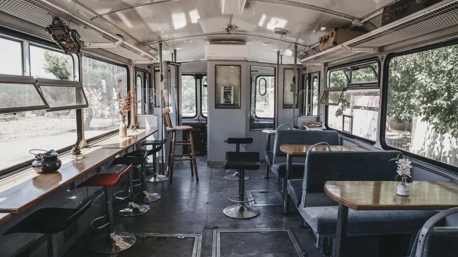 Das Innere eines alten, zum Café umgebauten Eisenbahnwaggons mit Sitzbänken und Tischen