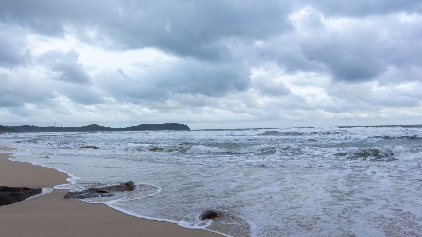 Monsoon surf breaking on a Thai island beach under a heavy overcast sky