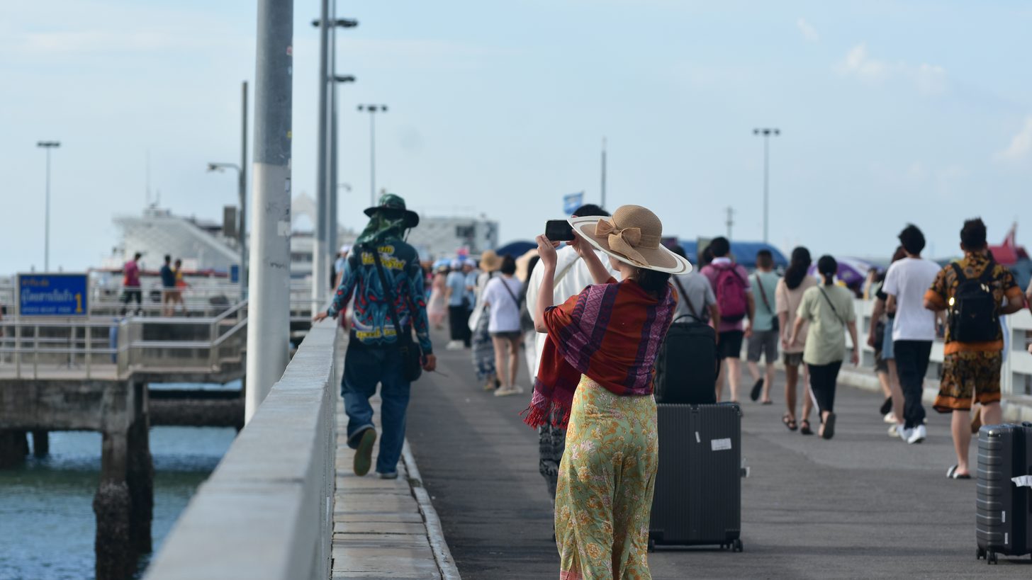 Visitors walking with luggage along Pattaya's crowded pier