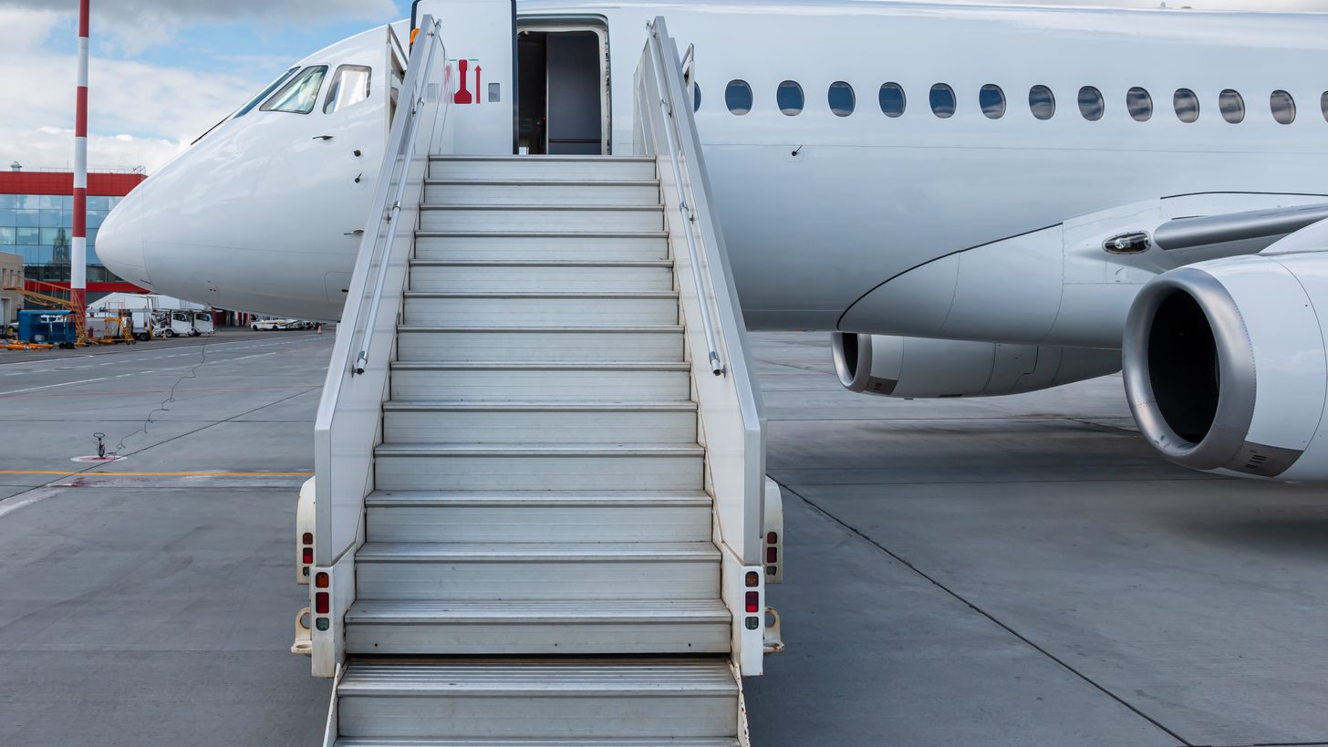 A passenger aircraft with boarding steps on an airport apron