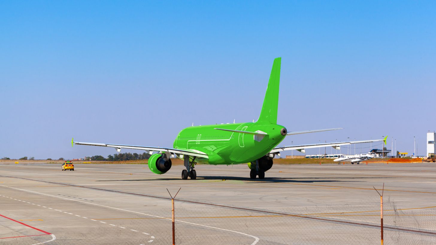 A passenger aircraft taxiing at a small airport with a low-rise terminal behind