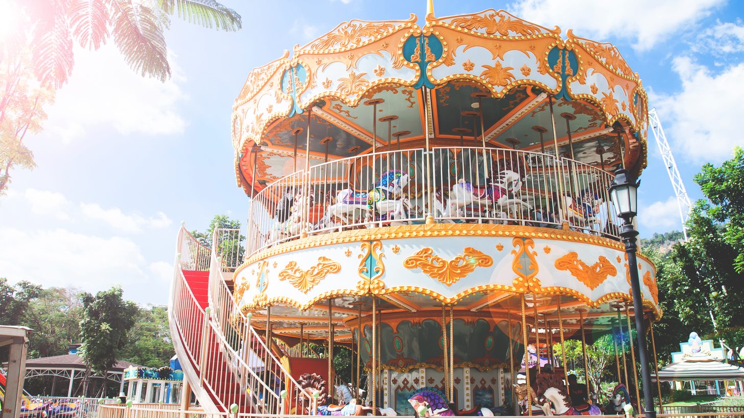 An ornate double-decker carousel at an outdoor family attraction park
