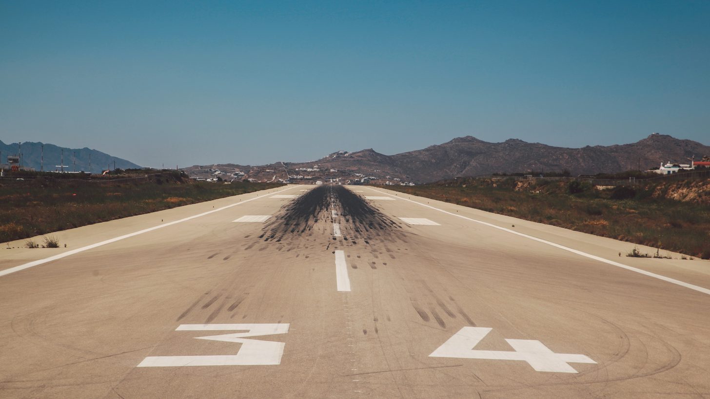 Tyre marks and centreline markings on an airport runway under a clear sky