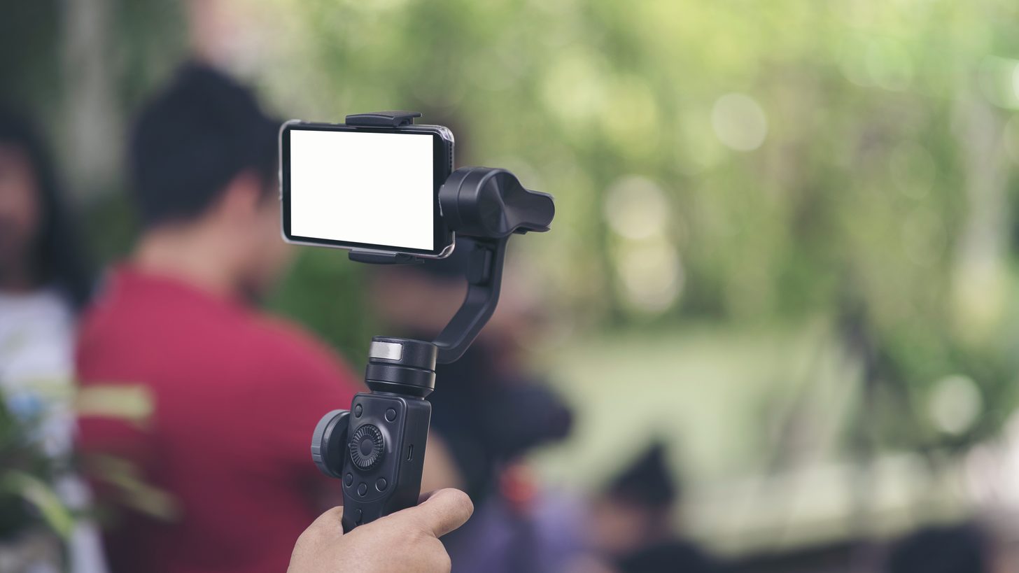 A smartphone mounted on a handheld gimbal, filming outdoors