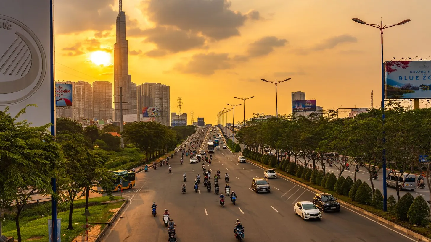 ホーチミン市の大通りの夕方の交通。金色の空を背にランドマーク81が立つ