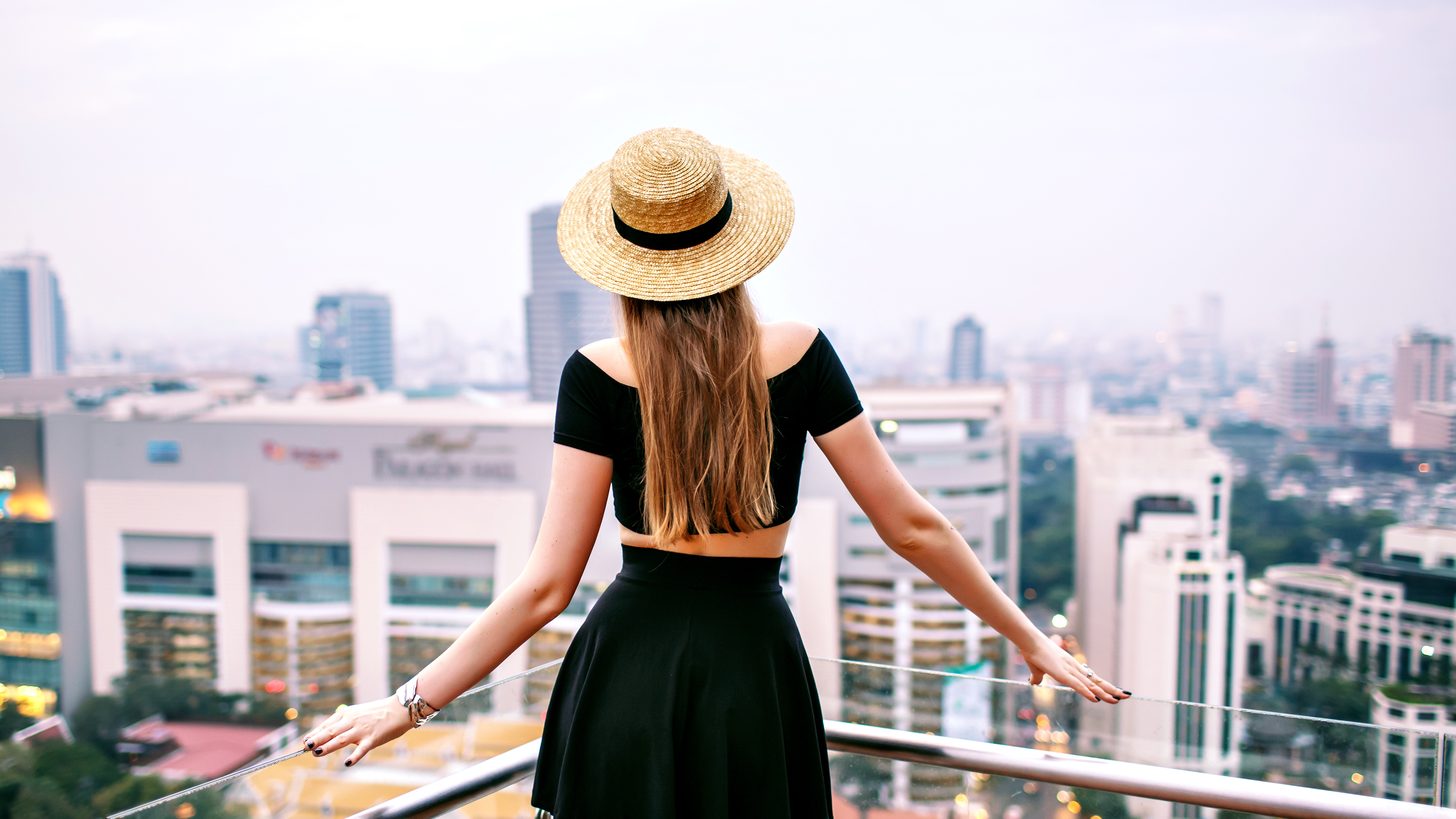 A traveller looking out over the Bangkok skyline from a rooftop terrace