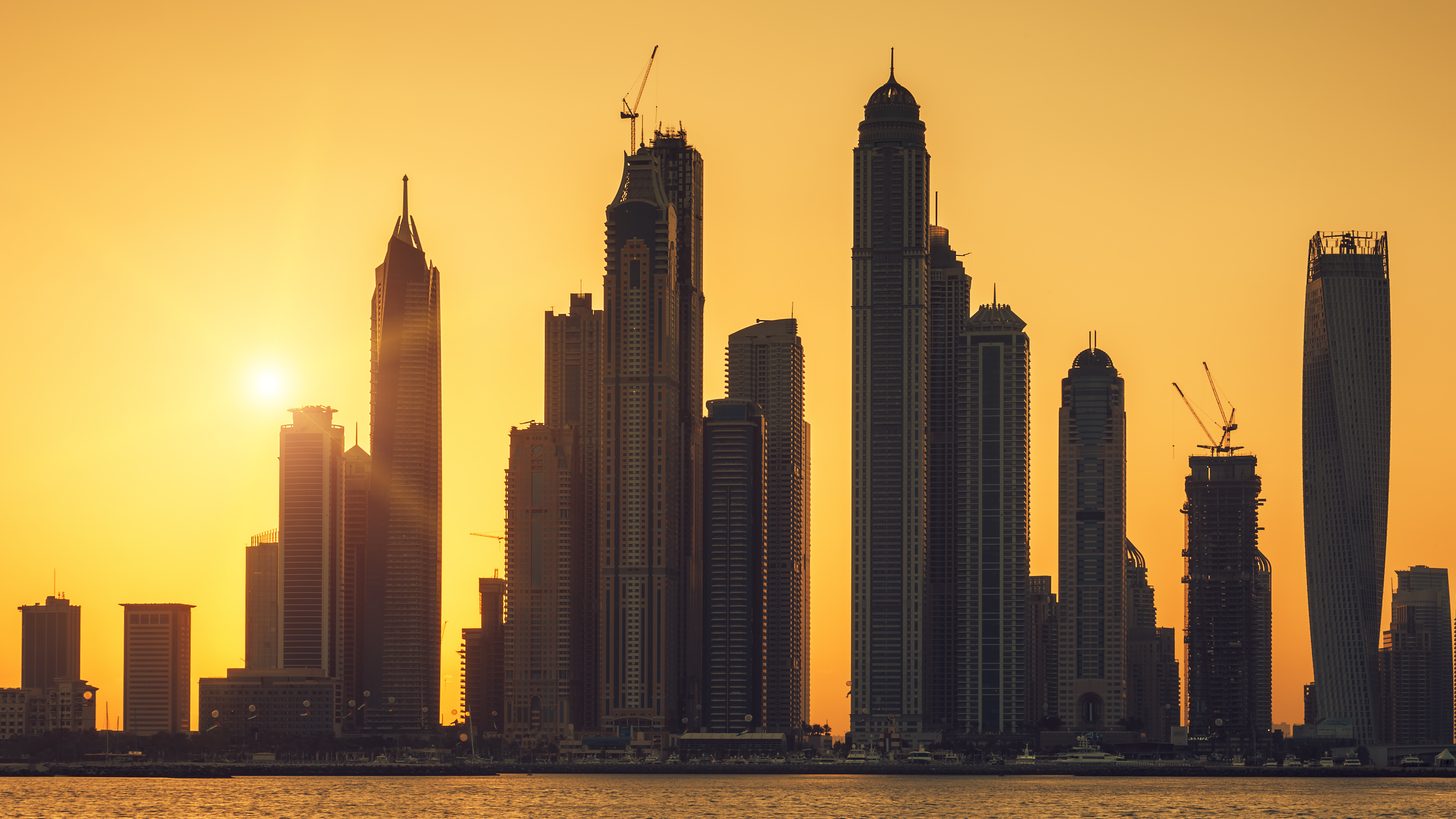 The Dubai skyline at sunrise seen across the water