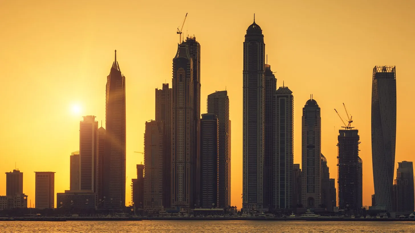 The Dubai skyline at sunrise seen across the water