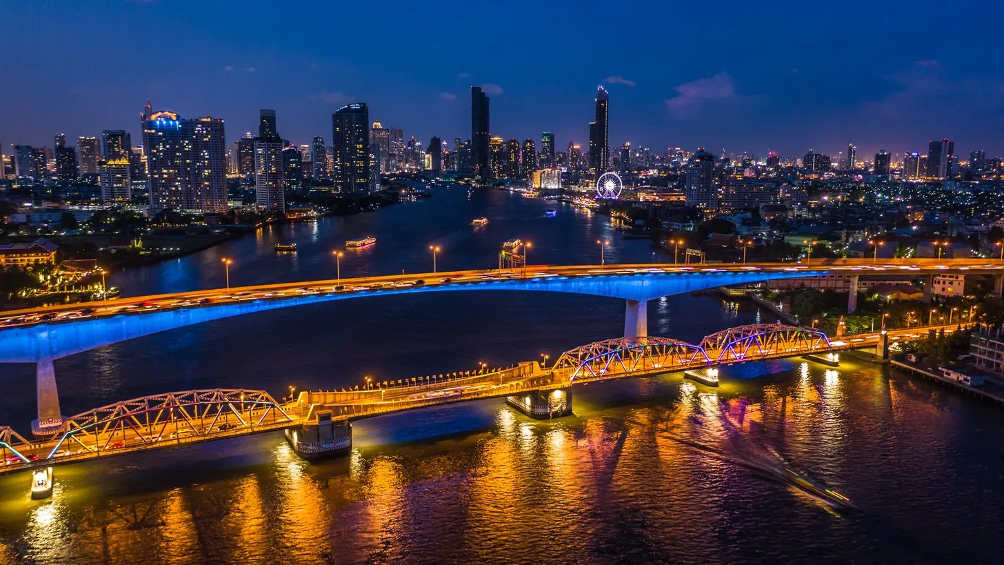 Luftaufnahme der Skyline von Bangkok bei Nacht, der Chao Phraya windet sich durch die beleuchtete Innenstadt