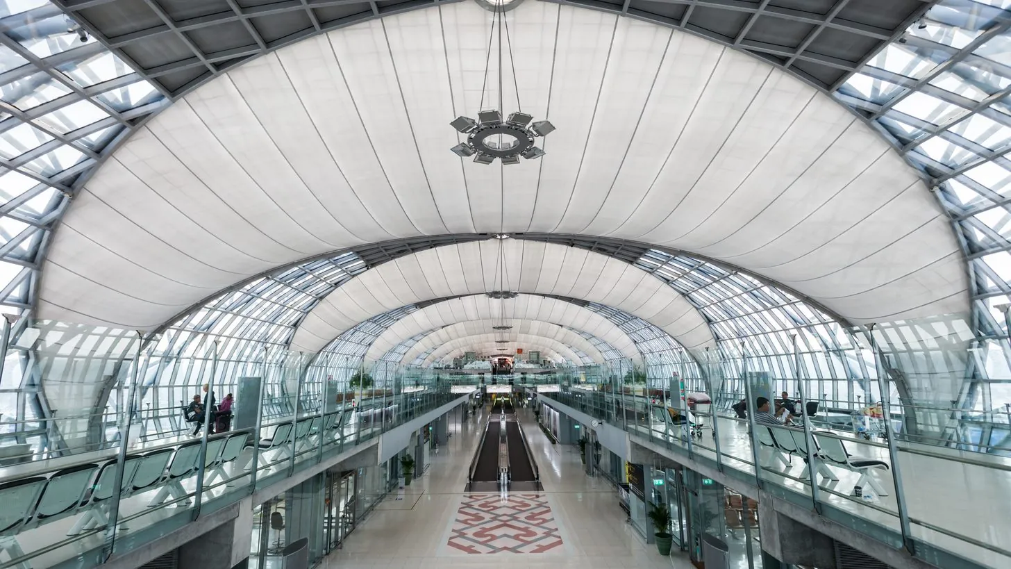 Die lange gewölbte Halle des Hauptterminals am Flughafen Suvarnabhumi, von einer oberen Ebene aus gesehen, mit einem Laufband in der Mitte