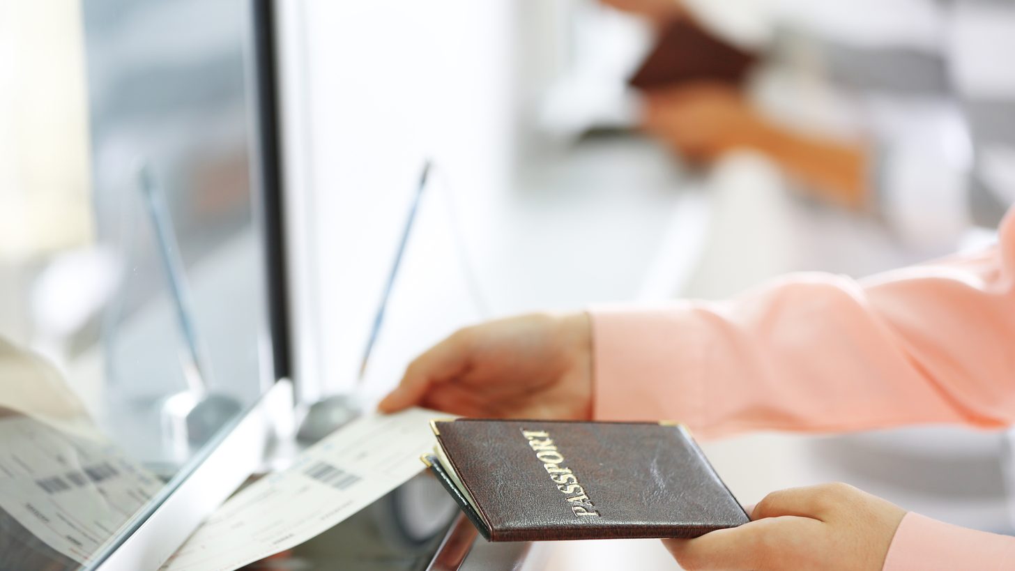 A passport and boarding pass handed across an airport counter