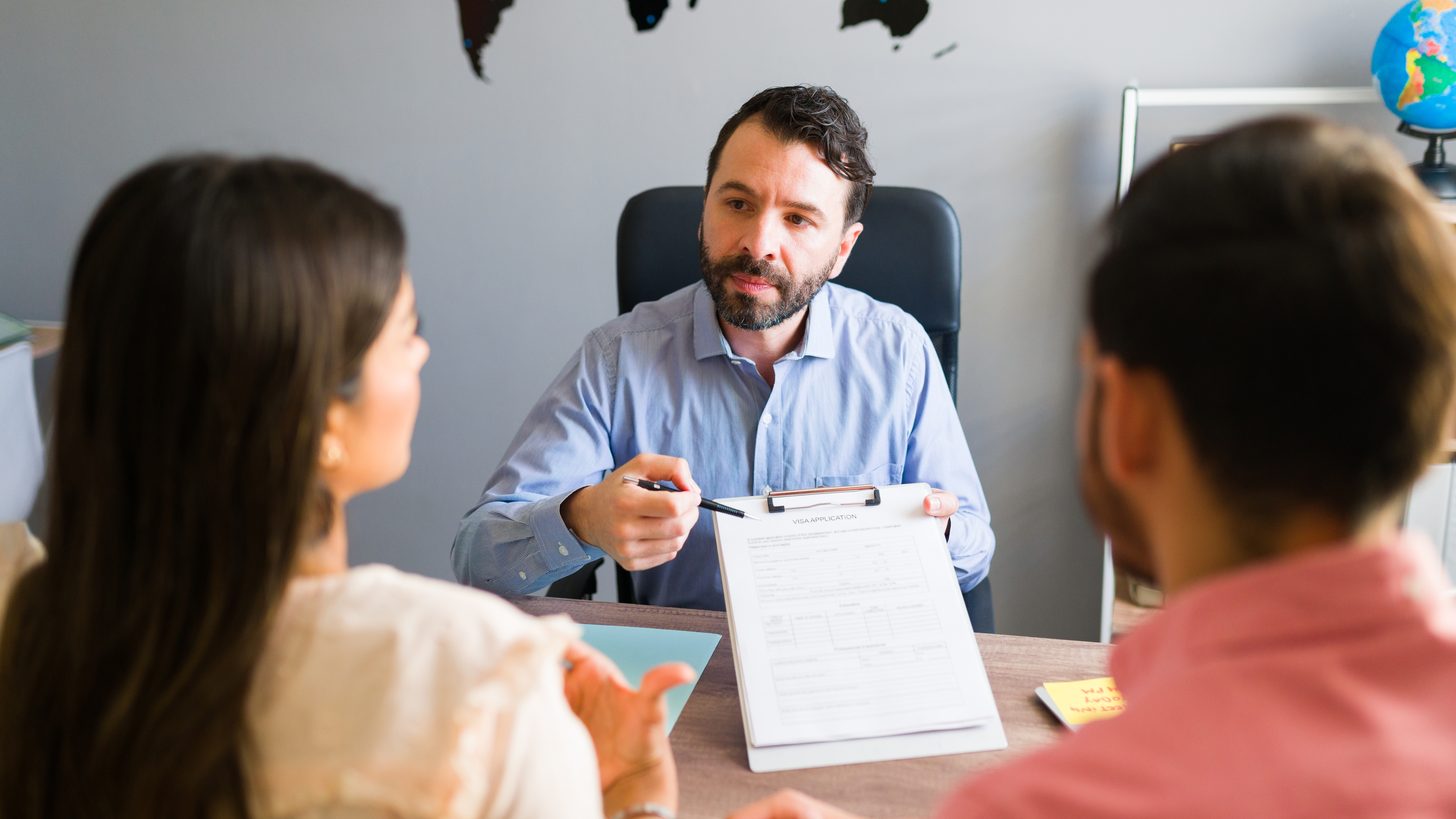 A travel agent showing travel documents to clients across an office desk