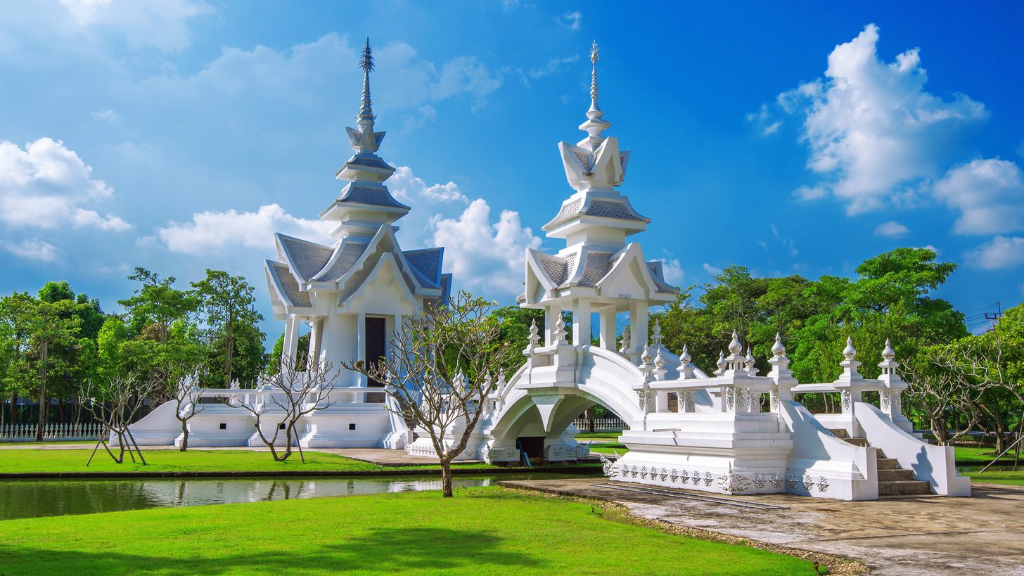 The white, mirror-studded facade of Wat Rong Khun in Chiang Rai against a blue sky