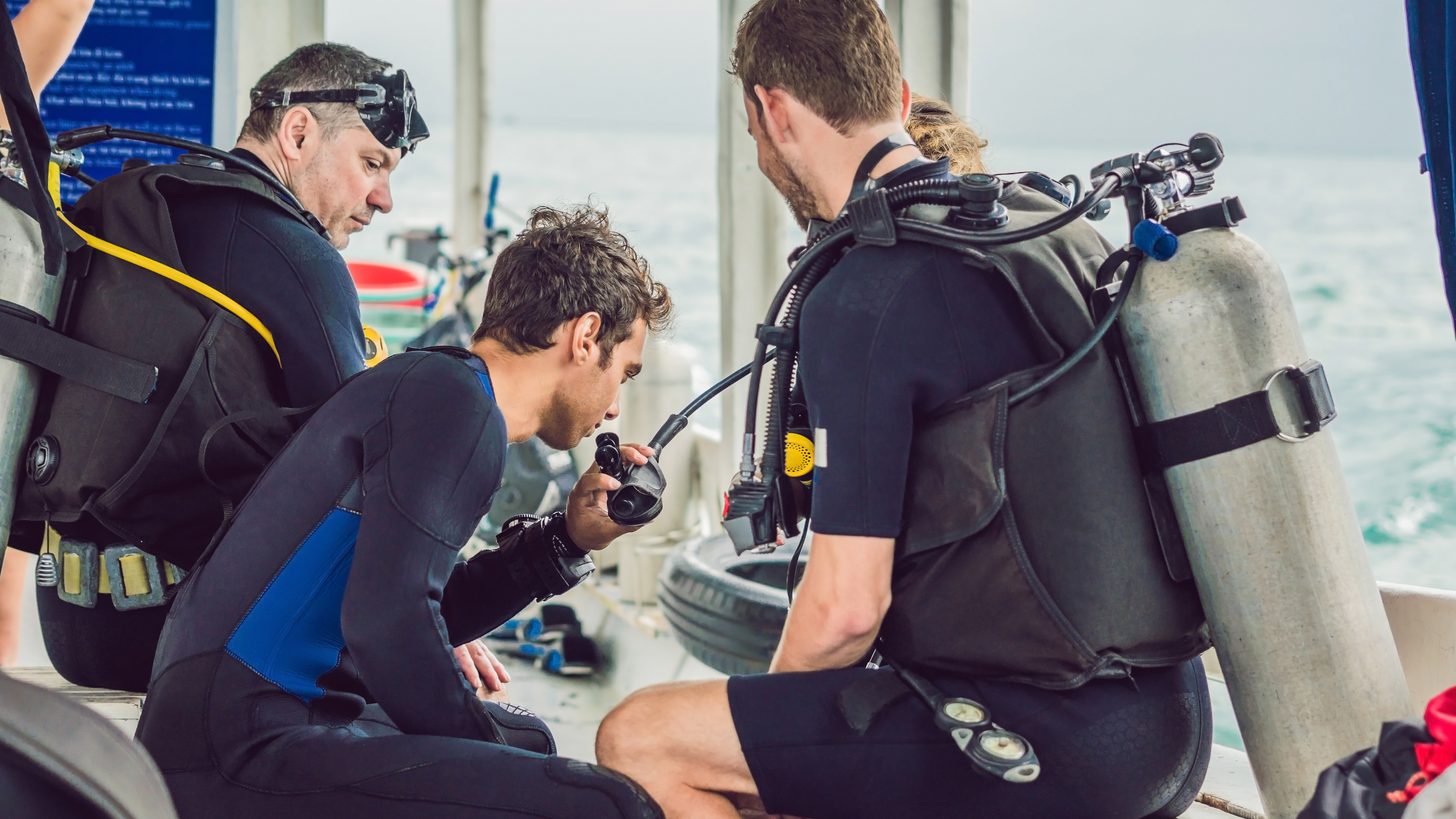 A diving instructor checking a beginner's scuba equipment before a dive