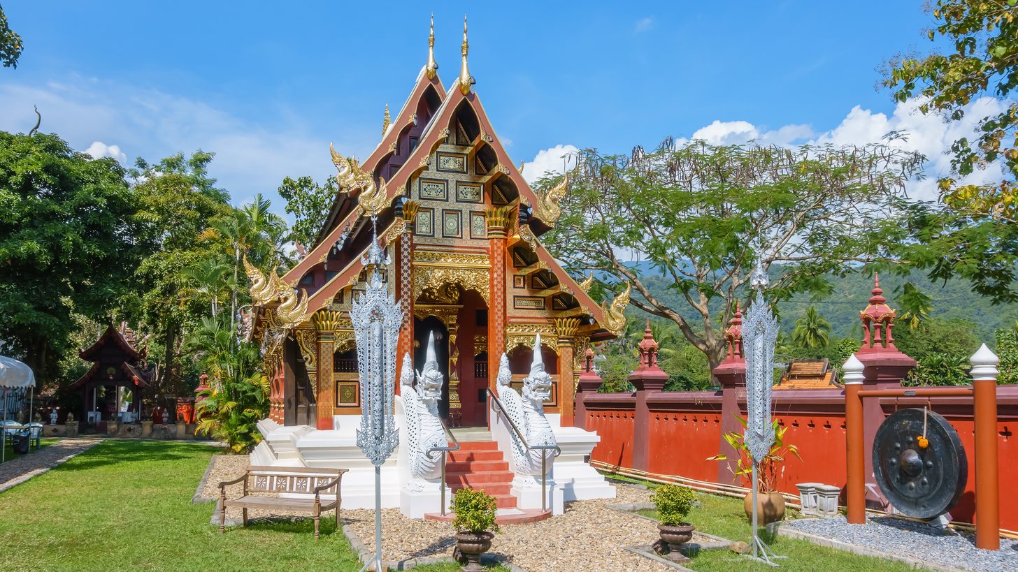 A Lanna-style temple chapel in Chiang Mai with tiered roofs and gilded detail under a clear sky