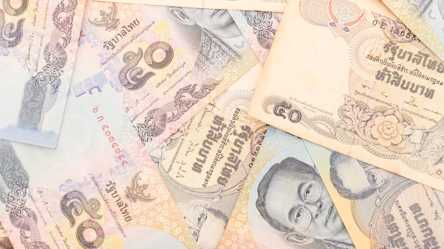 Billetes de baht tailandés desplegados en abanico sobre una superficie