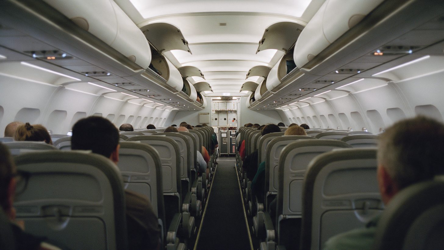 The aisle of a narrow-body aircraft cabin during boarding