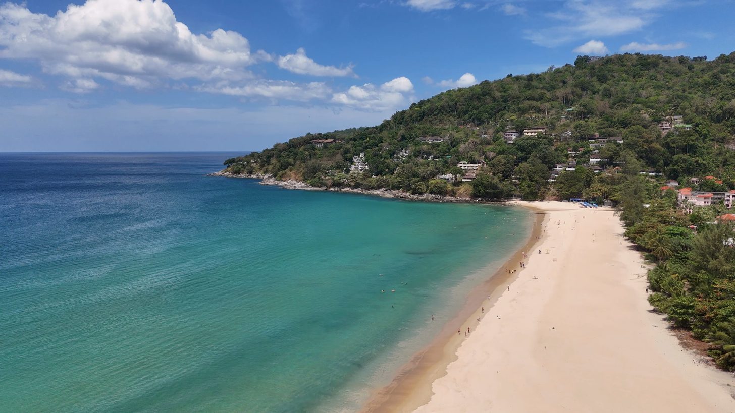 An aerial view of a long sandy beach and turquoise water on the Phuket coast
