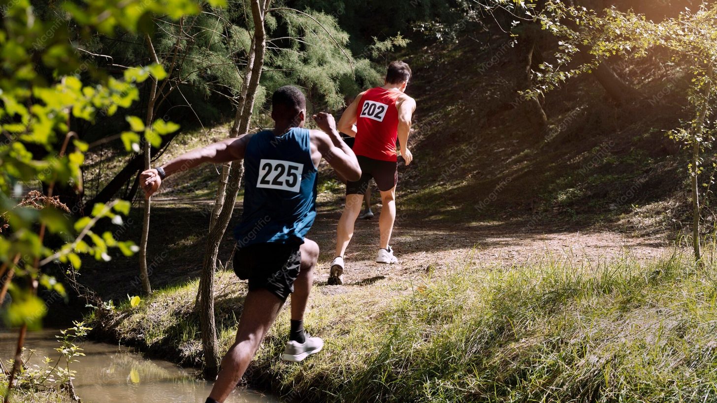 Runners with race bibs on a forest trail during a cross-country event