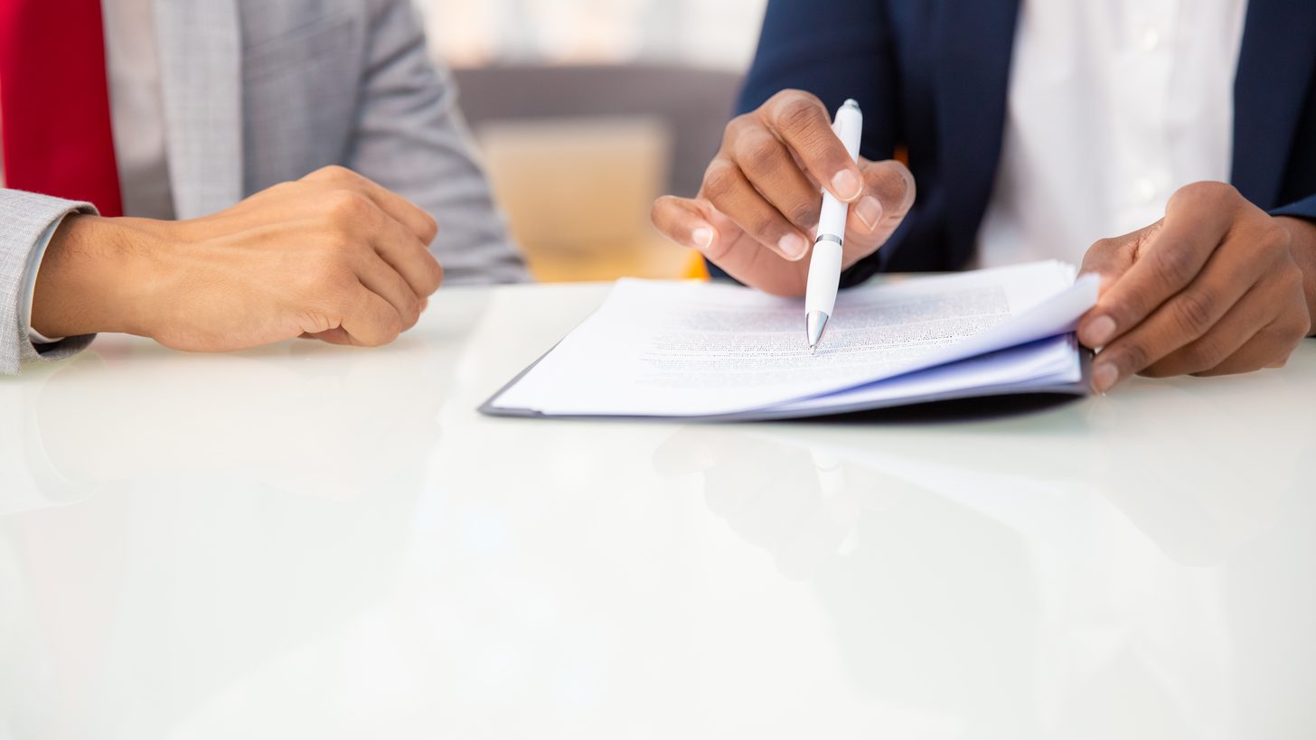 Two people reading through the pages of a contract at a desk
