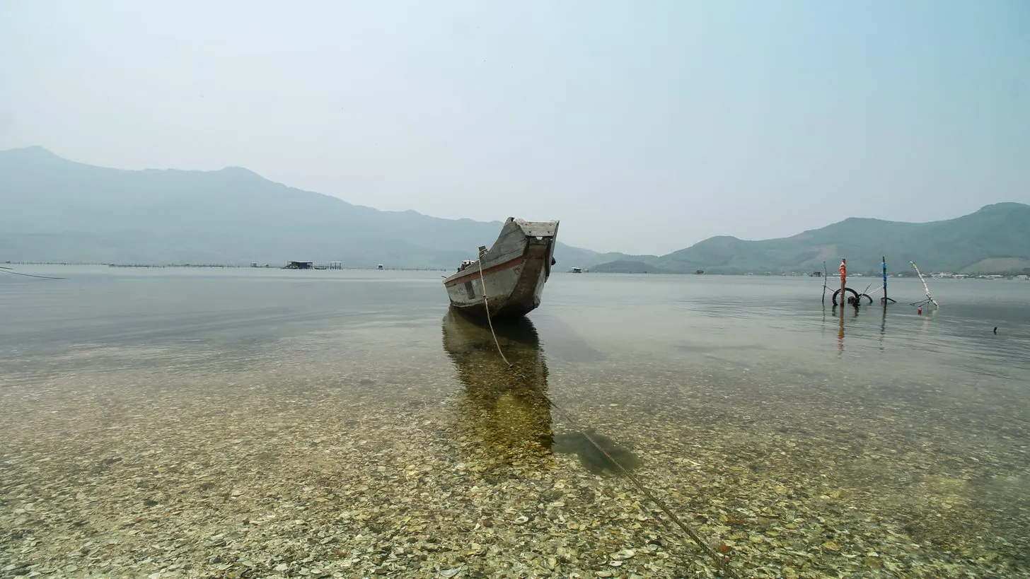 丘を背に、ベトナム中部の海岸の浅瀬に係留された木造の漁船
