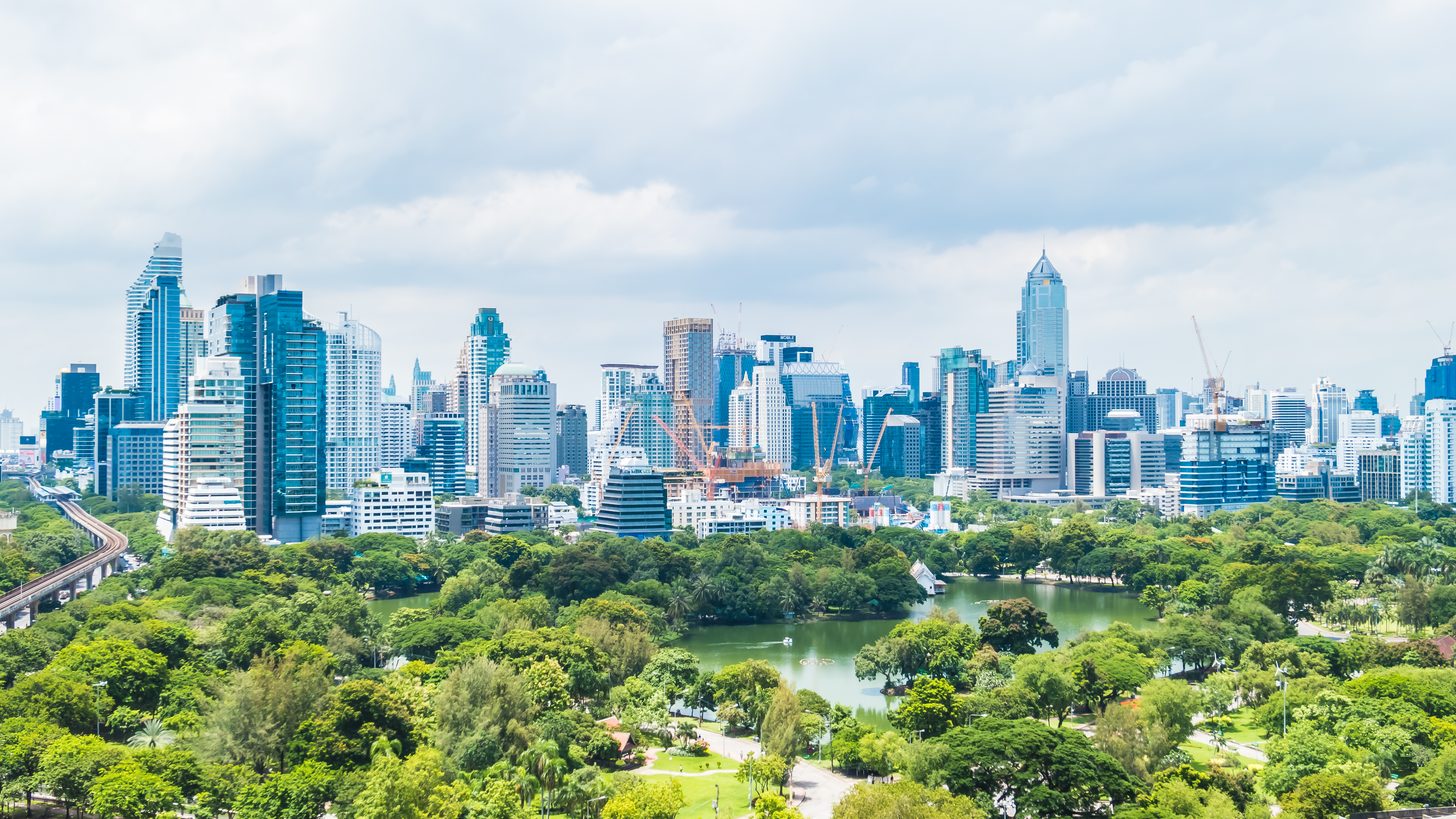 Bangkoks Hochhaus-Skyline über einem großen grünen Park mit See