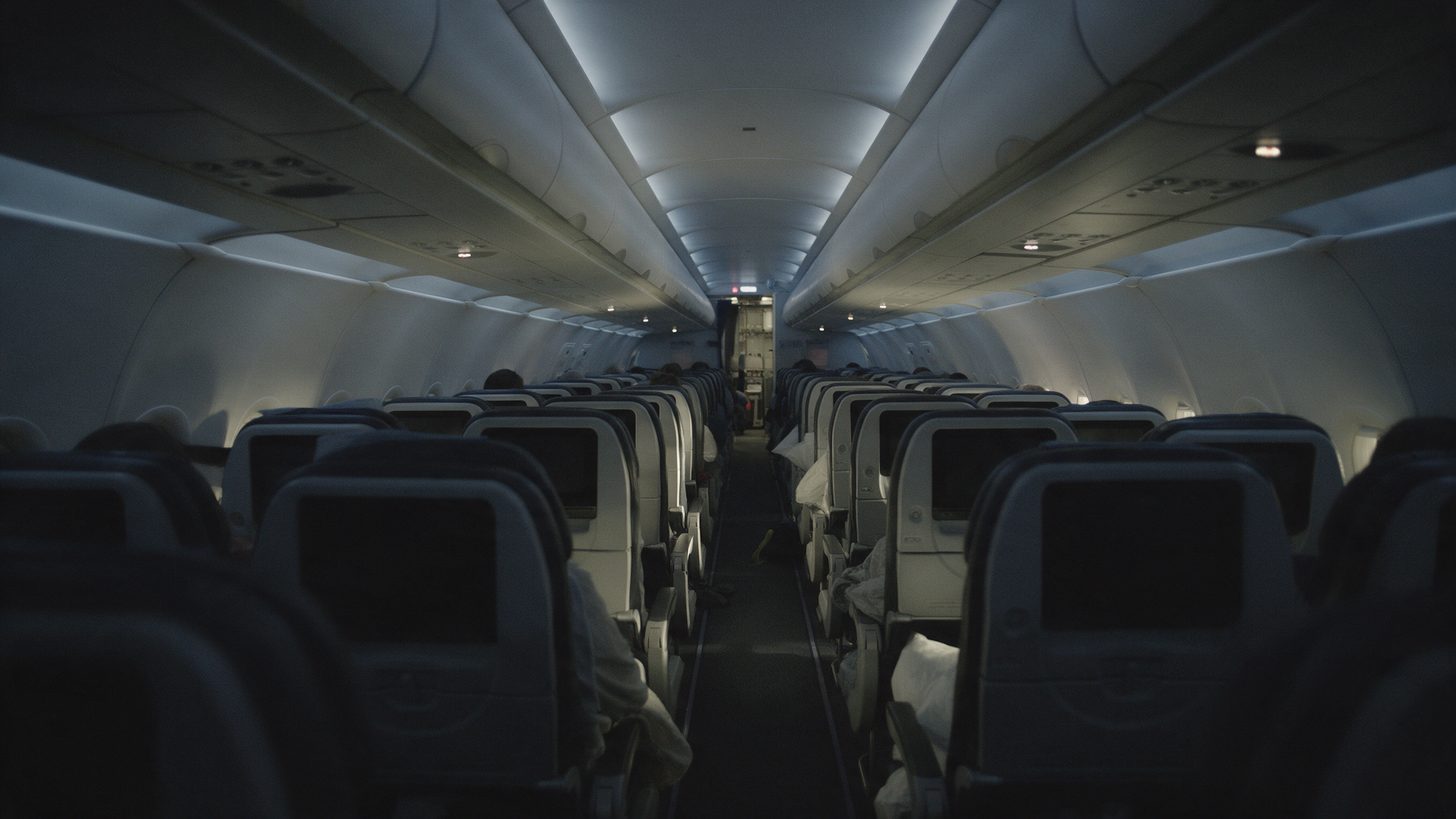 Rows of seats in a long-haul aircraft cabin with the lights dimmed for a night flight