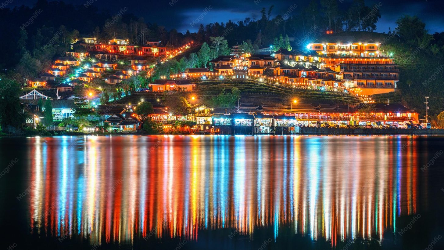 Les lumières du village de Ban Rak Thai reflétées dans un lac la nuit, dans la province de Mae Hong Son